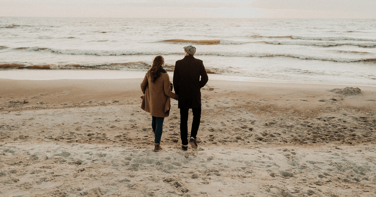 image of man and woman at the beach with coats on